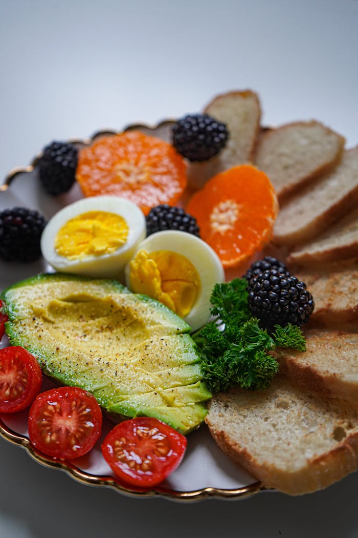 Vibrant breakfast plate with fresh avocado, eggs, and assorted fruits.