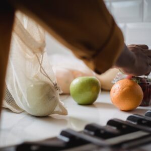 Person unpacking eco-friendly bag with fresh fruits in a modern kitchen.