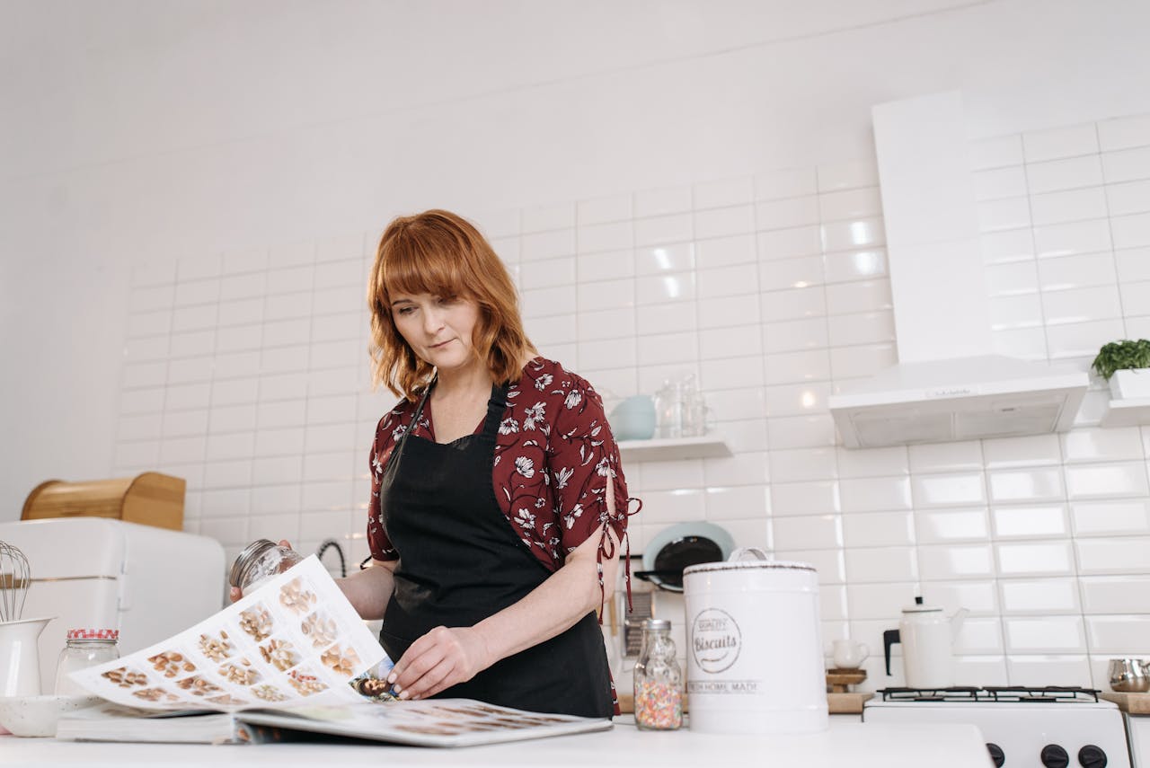 A woman in the kitchen examining a recipe book, preparing for baking.