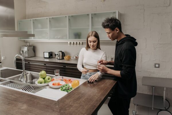Young couple managing diabetes with glucometer while preparing a healthy meal in a modern kitchen.